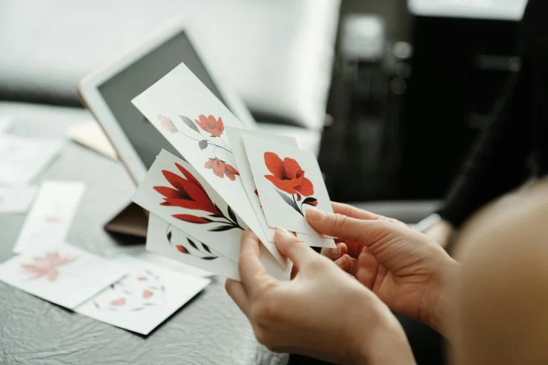 Person holding floral-themed custom stickers with red flower designs, showcasing artistic and creative uses for personalized stickers in Singapore.