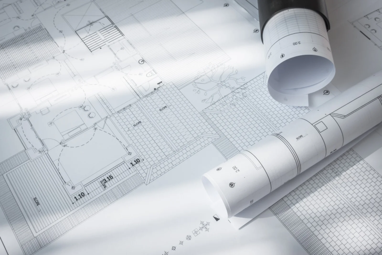 Rolled and unrolled A1 technical drawings and blueprints displayed on a table, showcasing precise architectural layouts by Pisti Prints.
