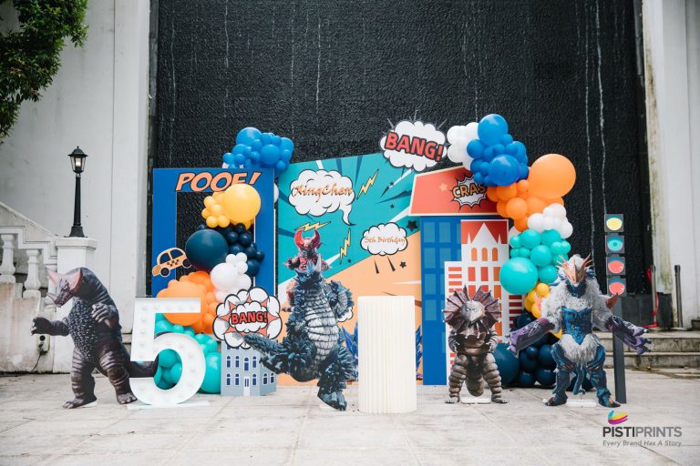 Colorful event-ready backdrop with cartoon city designs, balloons, and superhero-themed props for a child’s 5th birthday, showcasing creative backdrop printing services in Singapore.